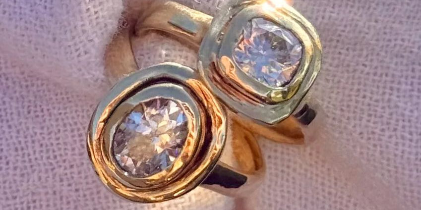 Gold ring with two prominent gemstones on a textured fabric background