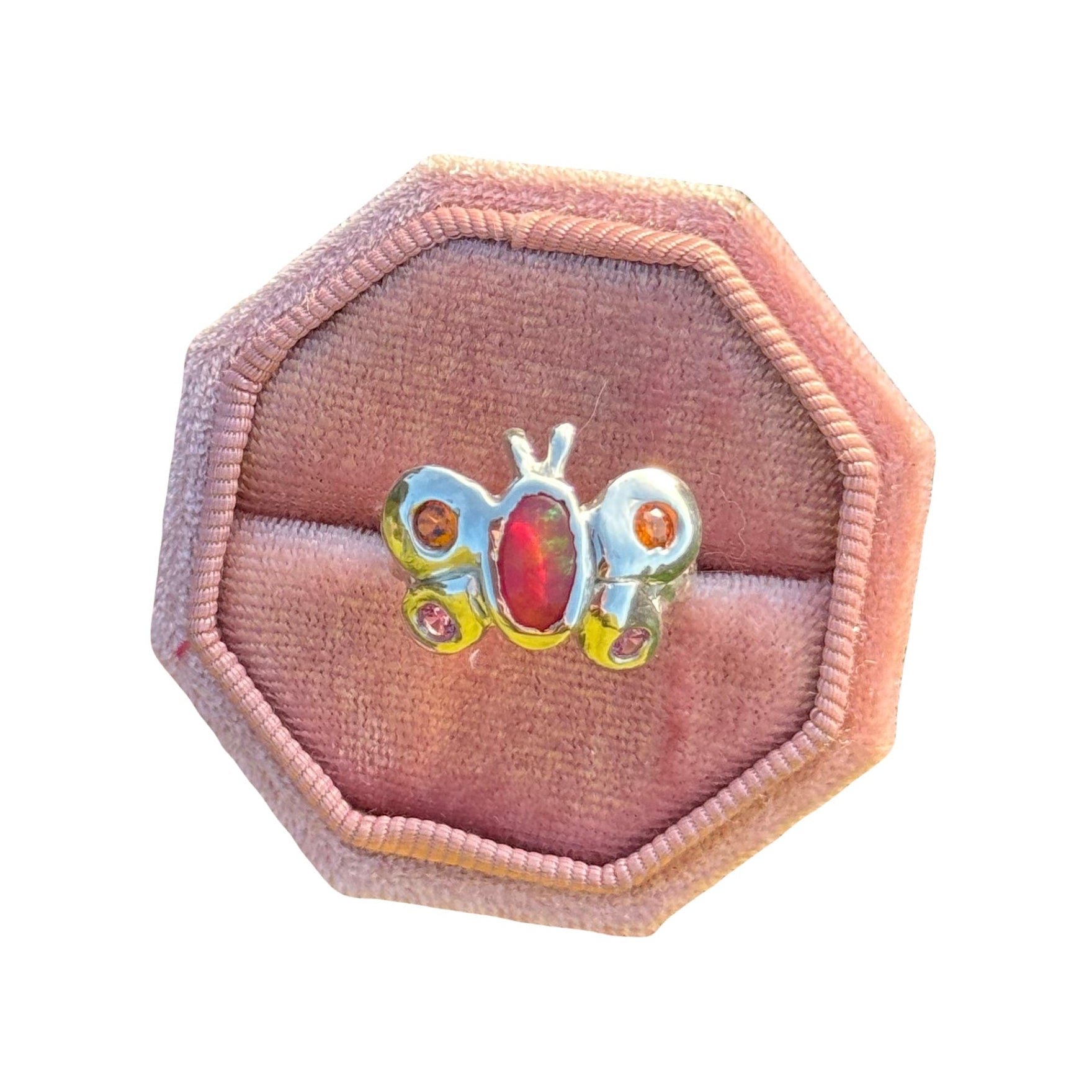 Butterfly-shaped ring in a pink velvet box on a white background