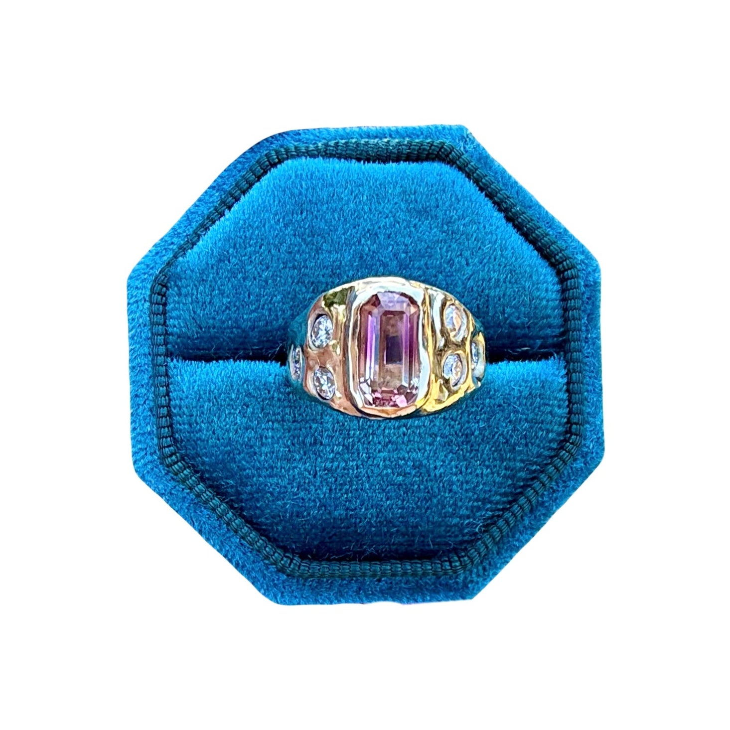 Ring with a pink gemstone in a blue velvet ring box on a white background