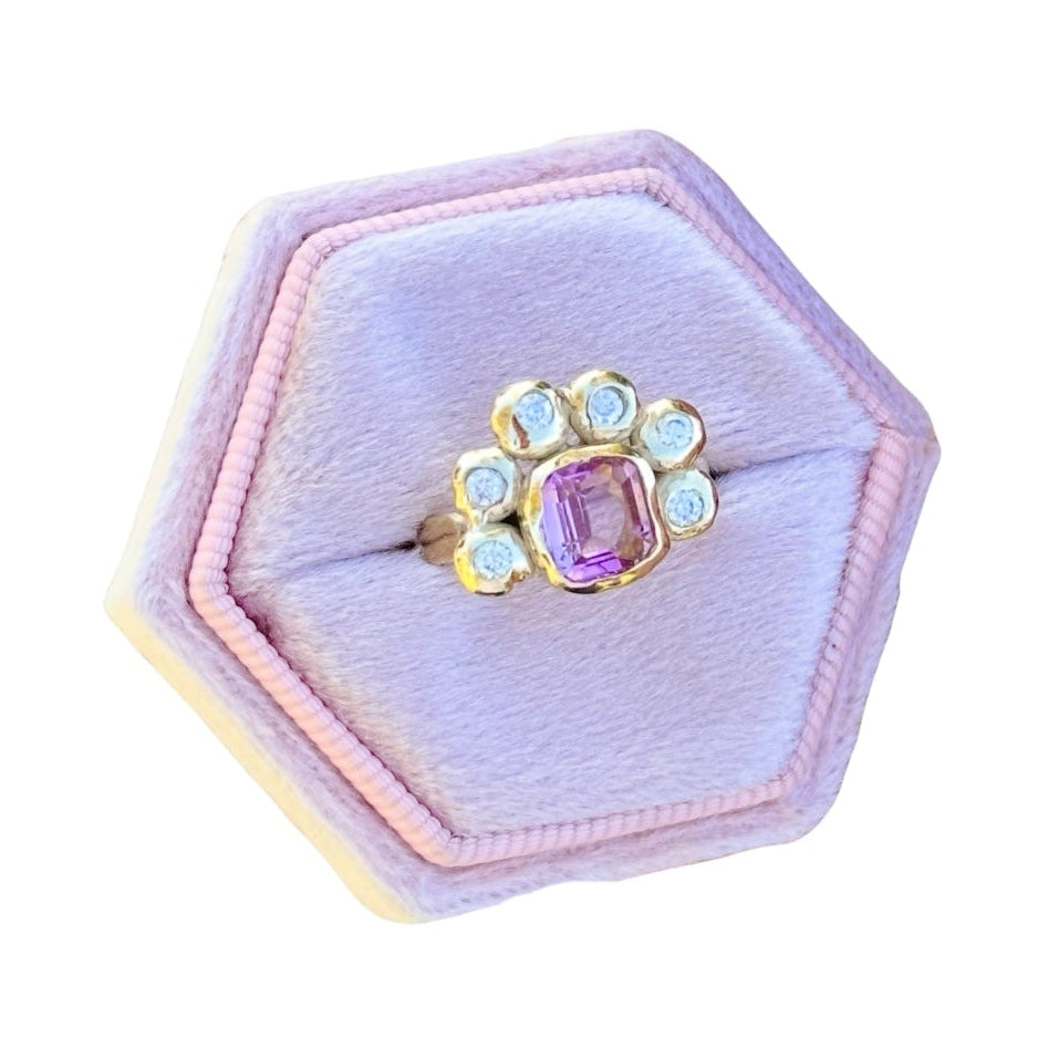 Hexagonal pink jewelry box with a ring featuring a pink gemstone on a white background