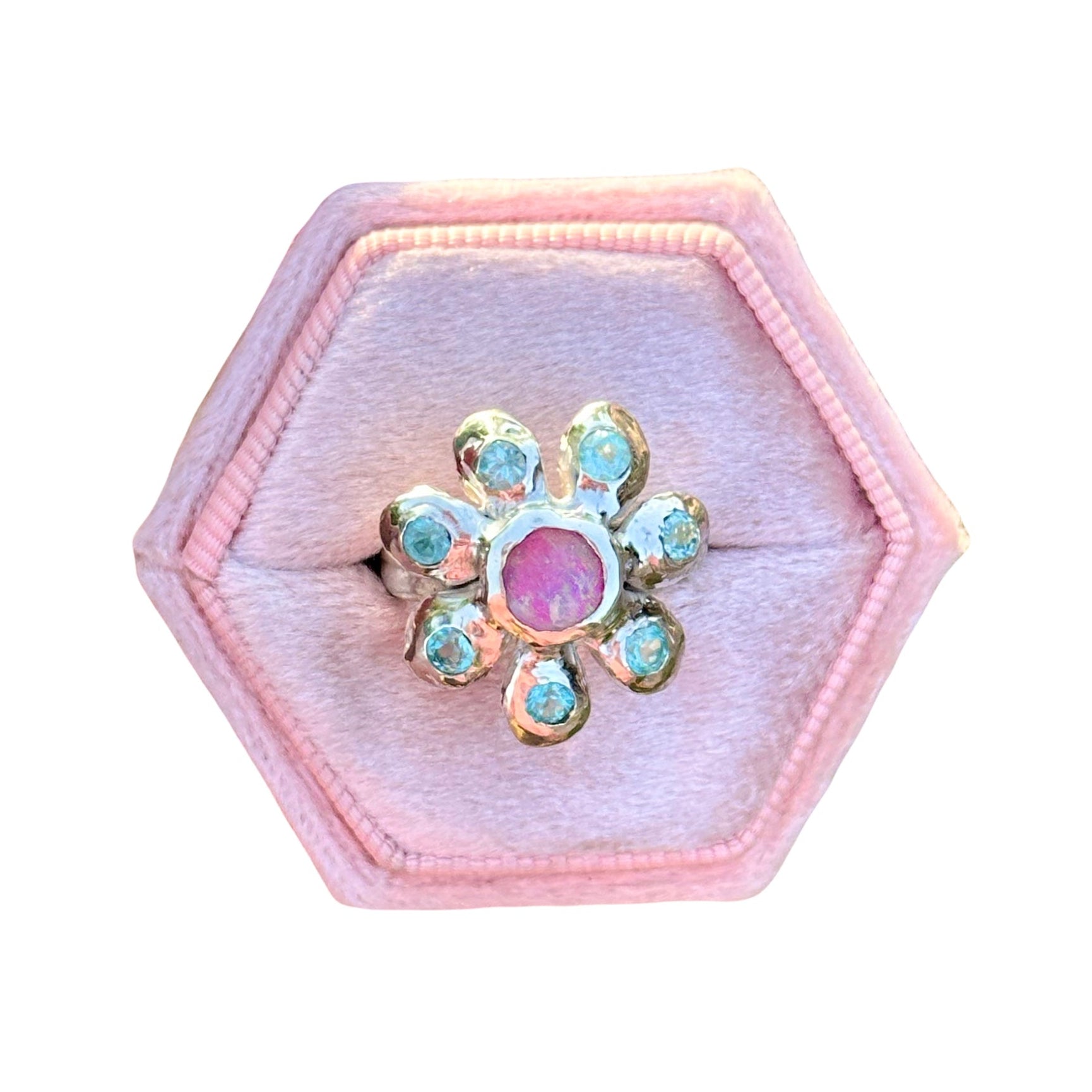 Hexagonal pink jewelry box with a decorative ring featuring a pink gemstone on a white background